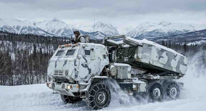 A military rocket launcher vehicle driving through heavy snow in a mountainous winter environment.